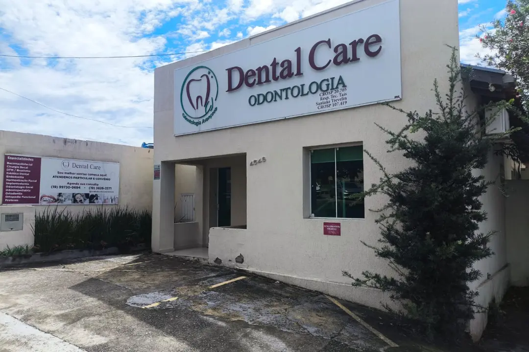 Fachada externa da clínica Dental Care Odontologia em Vinhedo, exibindo a placa principal com o logotipo, números de registro e a entrada do estabelecimento.